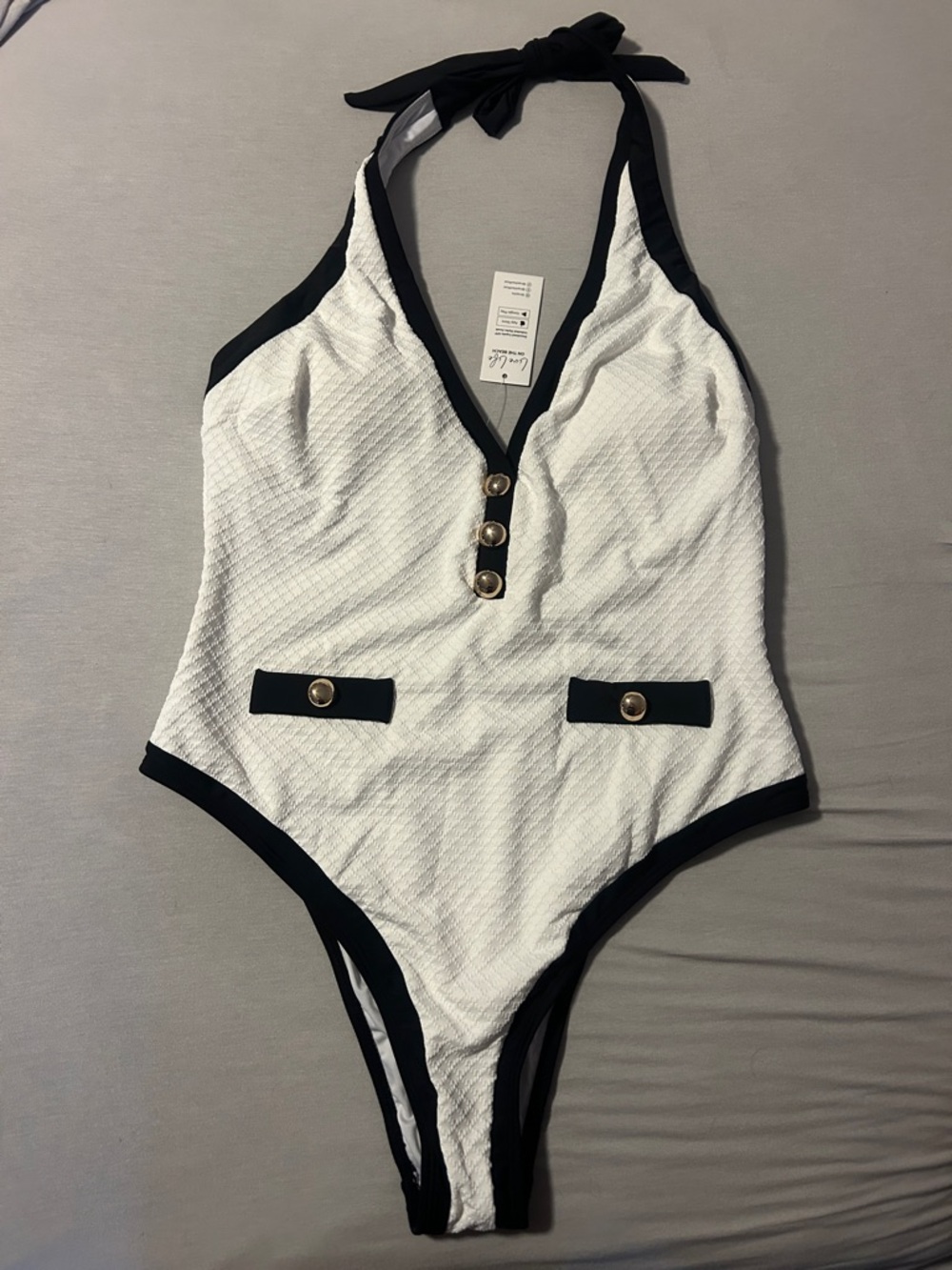 Cupshe White Textured One-Piece Swimsuit with Black Trim and Gold Buttons.